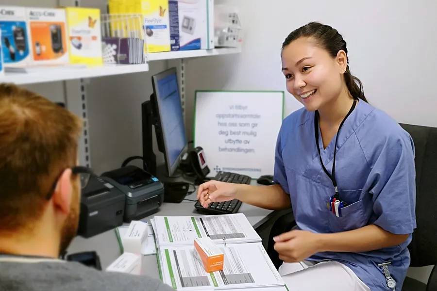 En kvinne som viser en mann noe på datamaskinen